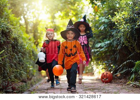 Kids Trick Or Treat On Halloween Night. Child At Decorated House Door With Autumn Leaf Wreath And Pu