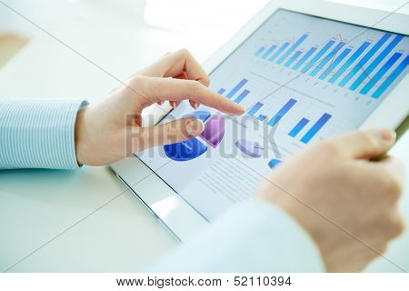 Close-up image of an office worker using a touchpad to analyze statistical data