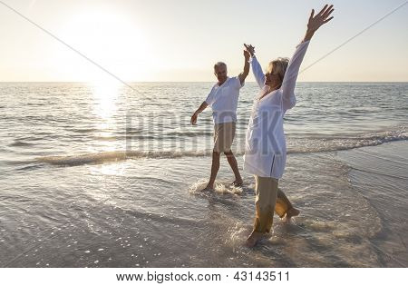 Anziano uomo e donna coppia felice ballando e tenendo le mani su una spiaggia tropicale deserta all'alba 