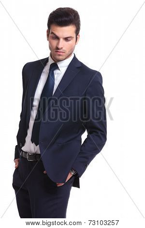 Portrait of a elegant business man looking down while holding his hands in pocket, on white background