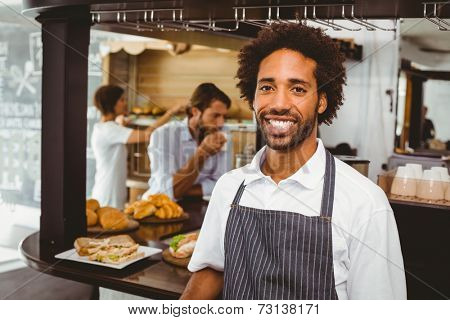 Handsome waiter smiling at camera at the coffee shop