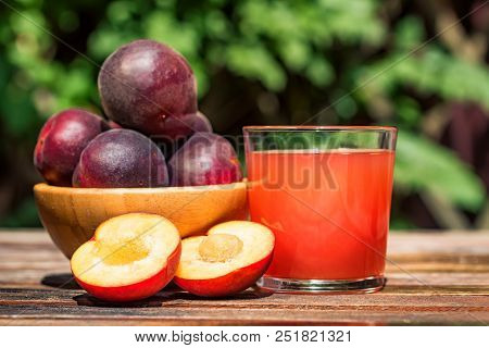 Close Up Juice Of Plumot, Mix Of Plum And Apricot, And Fresh Plumot On Wooden Table. Selective Focus