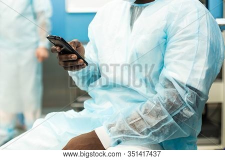 Portrait Of A Surgeon In Uniform And Medical Mask After The Operation Is Completed Sitting With A Ph