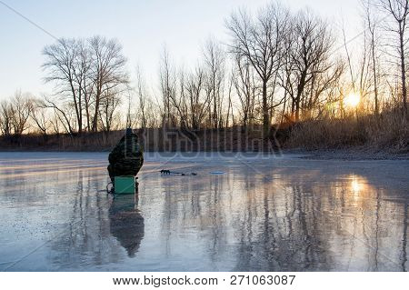 Beautiful Landscape Of Forest Lake. Fisherman Sitting On The Ice. The First Fishing From The Ice.