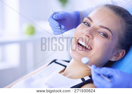 Young Female patient with open mouth examining dental inspection at dentist office.