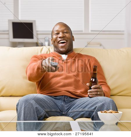 Man holding remote control and beer enjoying watching television