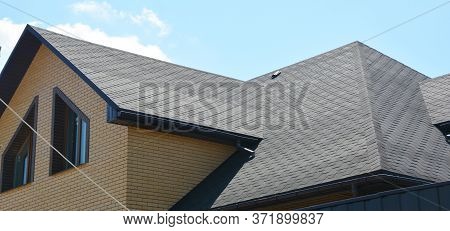 A Close-up On A Roof Problem Area Covered With Asphalt Roof Shingles And Irregular Shape Window On T