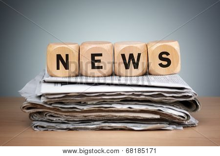 Newspapers folded and stacked with the word news in wooden block puzzle dice concept for newspaper, the media, press release and global communications