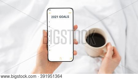 2021 New Year Goals Checklist. Hands Holding Smartphone With Future Goal And Plans List For Upcoming