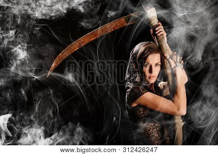 Girl In A Black Lace Cape With A Scythe Of Death Against The Background Of A Smoke. Concept