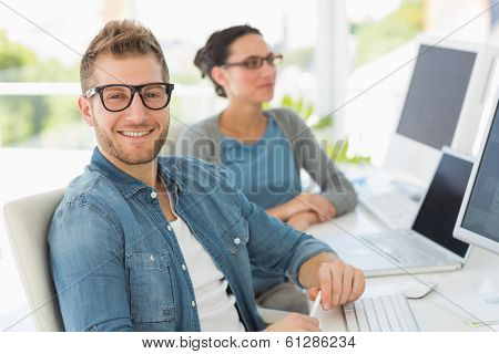 Team of smiling designers with man looking at camera in creative office