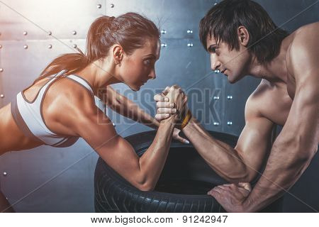 Athlete muscular sportsmen man and woman with hands clasped arm wrestling challenge between a young