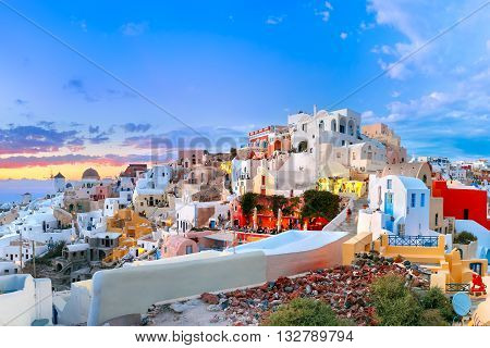 Picturesque panorama, Old Town of Oia or Ia on the island Santorini, white houses, windmills and church with blue domes at sunset, Greece