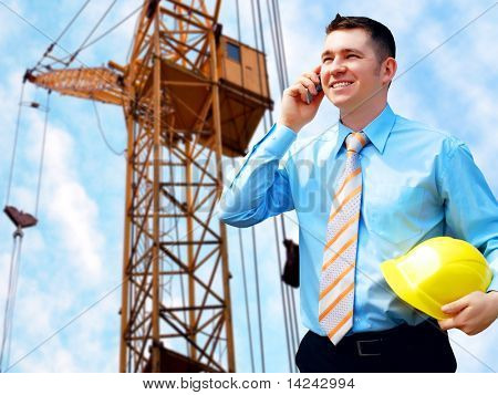 Young architect wearing a protective helmet standing on the building background