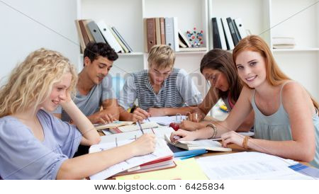 Sorridendo gli adolescenti che stanno studiando In biblioteca