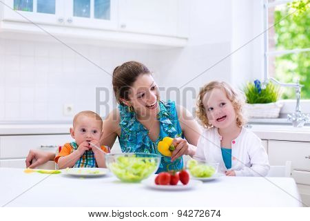 Mother And Children Cooking In A White Kitchen