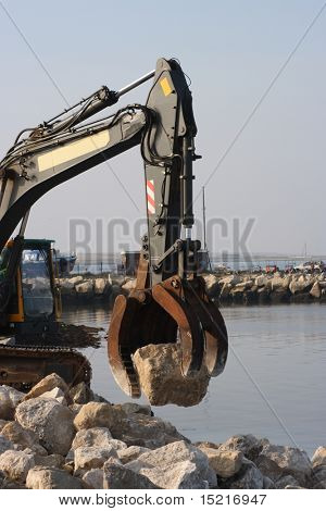 Boulders being positioned to strengthen a coastal sea wall, defense against rising sea levels due to global warming.