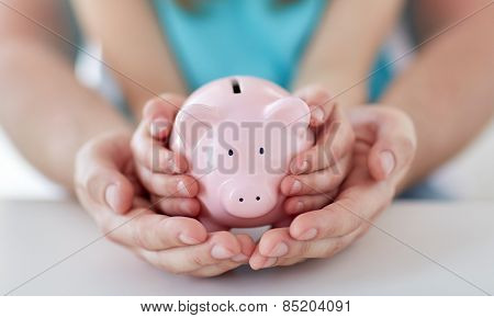 family, children, money, investments and people concept - close up of father and daughter hands holding pink piggy bank