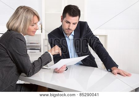 Successful teamwork: business man and woman sitting at desk talking about reports and finance.