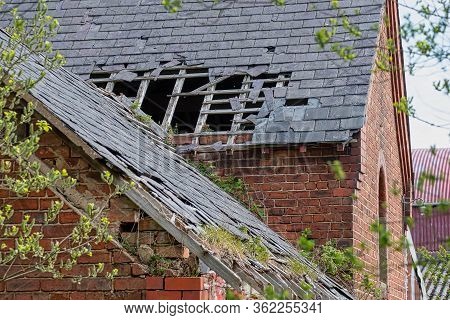 Damaged Slate Roof Tiles On A Pitched Roof On A Derelict House