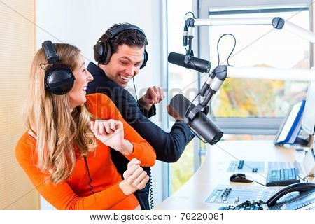 Presenters or moderators - man and woman - in radio station hosting show for radio live in Studio