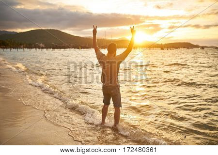 cheering farang man passionately observing sunset by himself in thailand