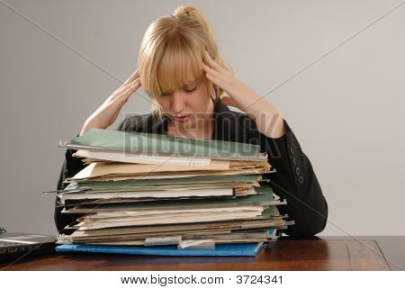 Stressed Businesswoman With Pile Of Files