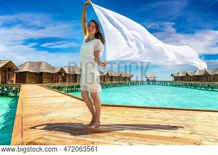 Beautiful Young Woman With Shawl Waving In Wind Over Tropical Beach Jetty (wooden Pier) In Maldives 