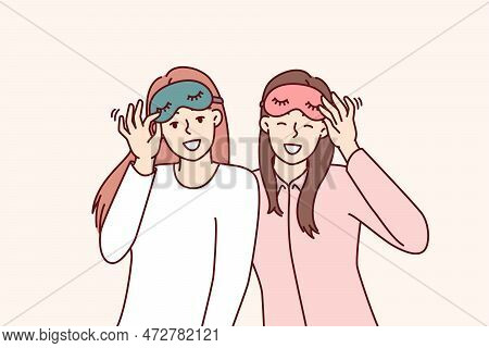 Friendly Girls In Pajamas With Sleep Masks Are Preparing To Relax In Comfortable Bedroom With Soft B