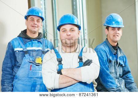 cheerful plasterboard workers team at a indoors wall insulation works