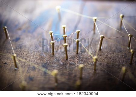 Linking entities. Network, networking, social media, internet communication abstract. Small networks connected to a larger network. Web of gold wires on rustic wood.?Shallow depth of field.