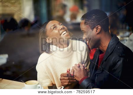 Laughing young couple in cafe having a great time together view through cafe window