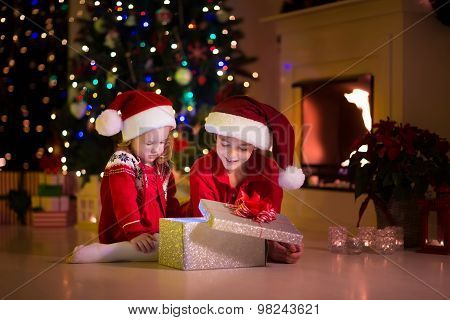 Kids Opening Christmas Presents At Fireplace