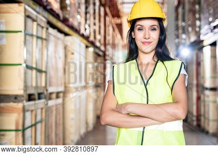 Portrait white caucasian warehouse female worker woman stand and cross arm with confidence smile in large warehouse distribution center. Business warehouse and logistic concept.