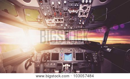 Aircraft interior, cockpit view inside the airliner. Point of view from a pilot place in a plane. Sunny sky horizon view from an airplane front glass.