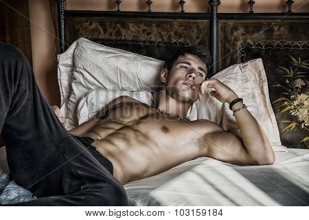 Shirtless sexy male model lying alone on his bed