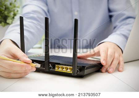 Man plugs Ethernet cable into router. router wireless wire broadband home office cable plug concept