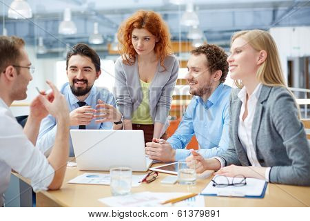 Group of business partners listening to their colleague explanations at meeting