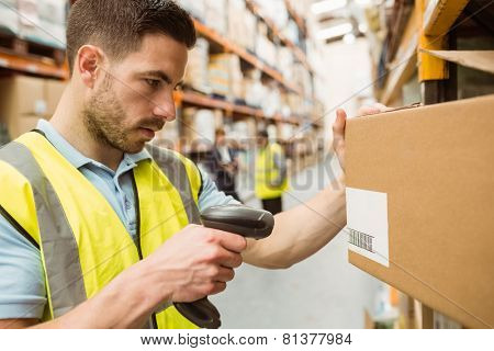 Warehouse worker scanning barcodes on boxes in a large warehouse