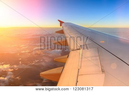 Aerial view of airplane flying above shade clouds and sky from an airplane fly during the sunset. View from the plane window of emotional moment during international travel around the world.