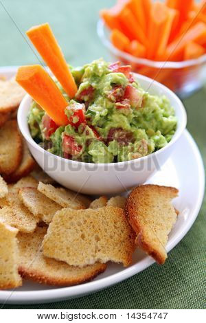 Avocado guacamole served with carrot sticks and bagel crisps - a healthy variation of this delicious snack.