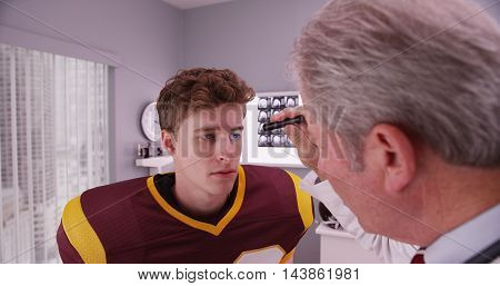 Mid-aged Doctor Examining Football Player After Concussion