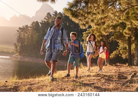 Children Walk By Lake With Parents On Family Hiking Adventure