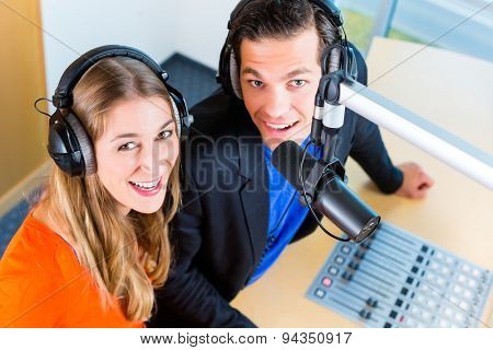 Presenters or moderators - man and woman - in radio station hosting show for radio live in Studio