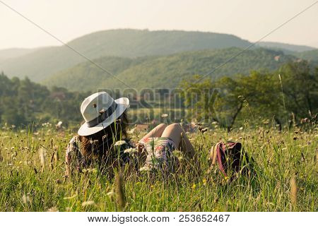 Woman on vacation relaxing in fields. Summer vacation. Young woman traveler in vacation in nature. Traveler in vacation with backpack in nature. Girl traveler relaxes in fields in vacation. Traveler. Vacation . Backpack. Woman. Nature. Healthy lifestyle