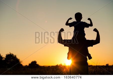 Father And Son Playing In The Park At The Sunset Time.