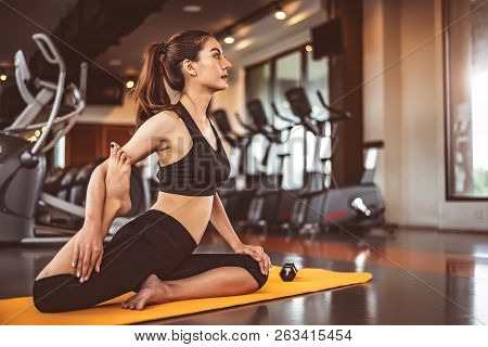 Woman Doing Bending Legs Yoga In Fitness Workouts Training Gym Center Background. Lifestyle Woman Si