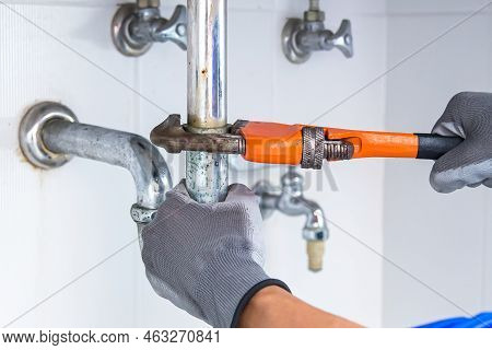 Technician Plumber Using A Wrench To Repair A Water Pipe Under The Sink. Concept Of Maintenance, Fix