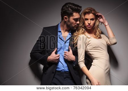 Attractive business man fixing his jacket while looking at his lover. The beautiful blonde woman is fixing her hair while looking at the camera.