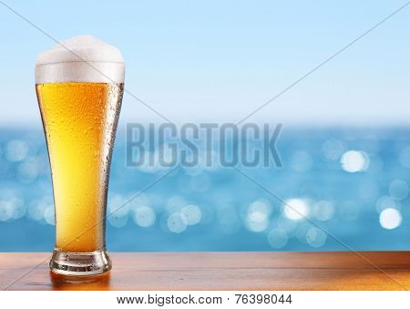 Photo of cold beer glass on the bar table at the open-air cafe.